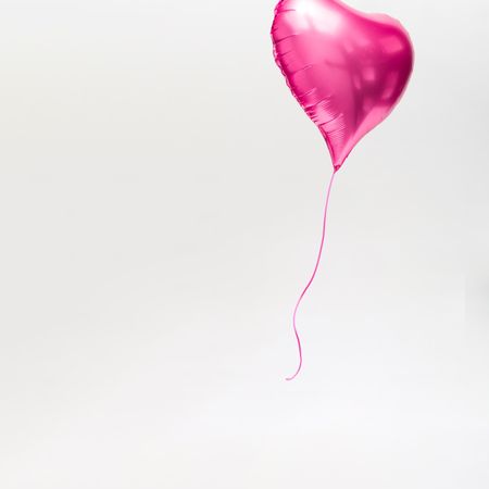 Pink heart balloon with string on light background