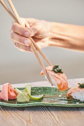 Unrecognizable person eating sake nigiri sushi