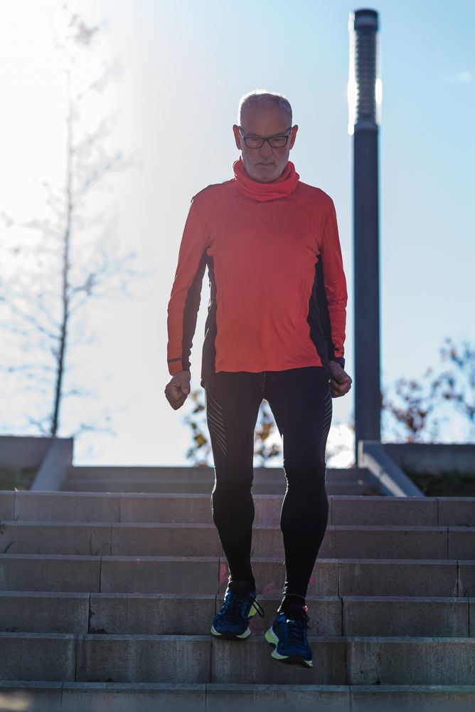 Older fit male walking down stairs in park on fall day