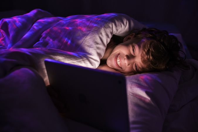 Delighted boy watching video on tablet in darkness