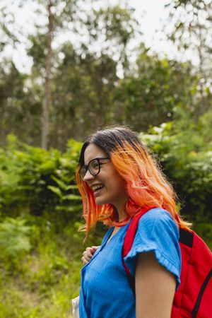 A young woman with orange hair smiles during a walk in a natural area in summer