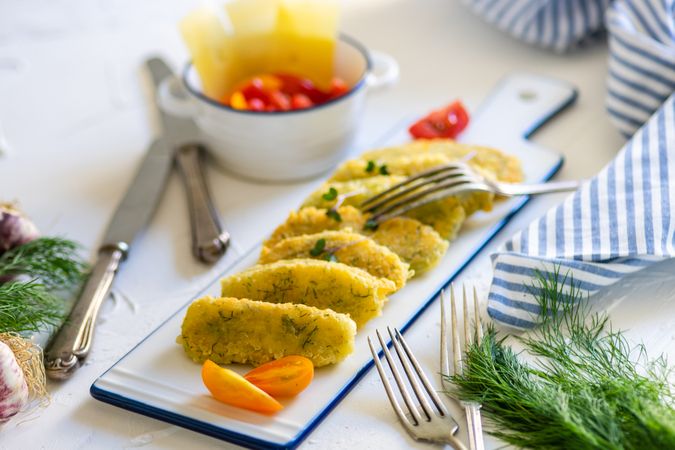 Appetizer of homemade cheese sticks served with cherry tomatoes & dill garnish