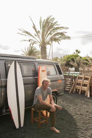 Man standing near surf boards and van