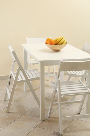 table with fruits and folding chairs in kitchen room