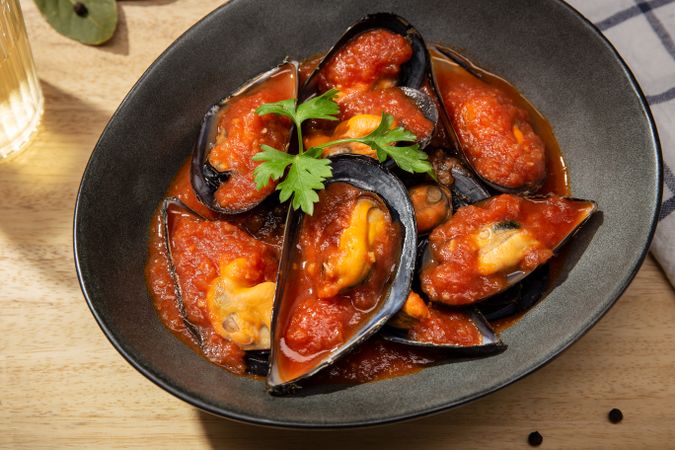 Cooked plate of mussels in tomato sauce on table