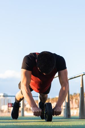 Muscular man doing ab wheel rollout exercise