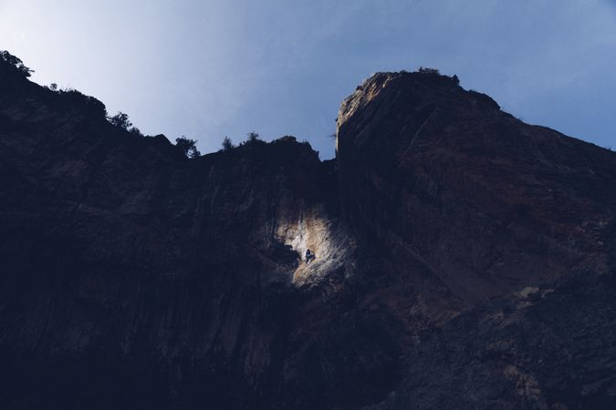 Illuminated spot on cliff with climber