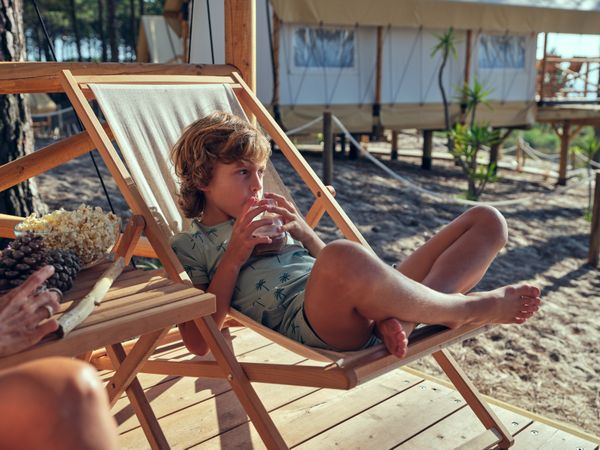 Boy drinking beverage on deckchair