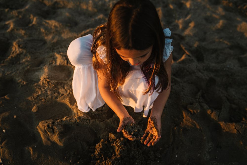 Adorable girl playing with sand on beach