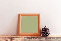 Plain square wooden picture frame with green interior leaning against wall mockup bEYLMb
