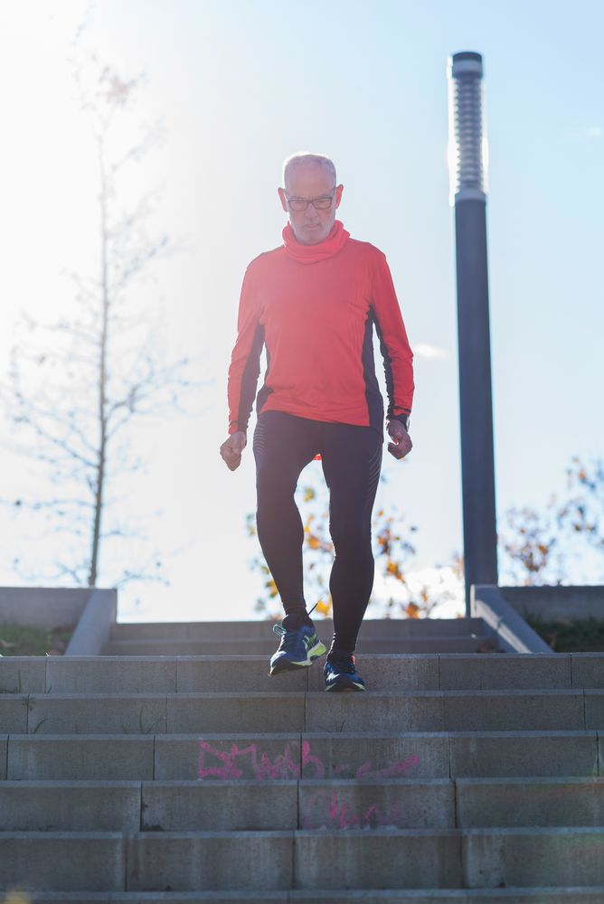 Older fit male walking down stairs in park outside