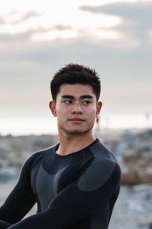 Young sportsman stretching near sea