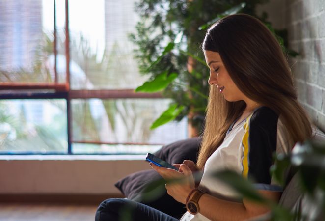 Side view of young woman using smartphone at home