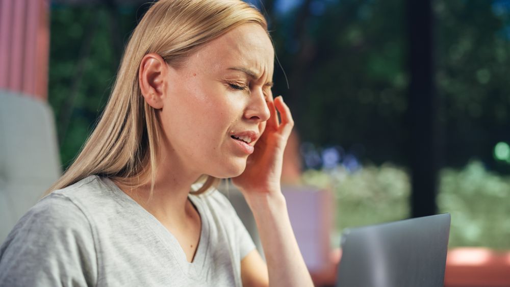 Human Going Through Headache: Close Up of a Female Working on Laptop Computer and Experiencing Discomfort and Migraine.