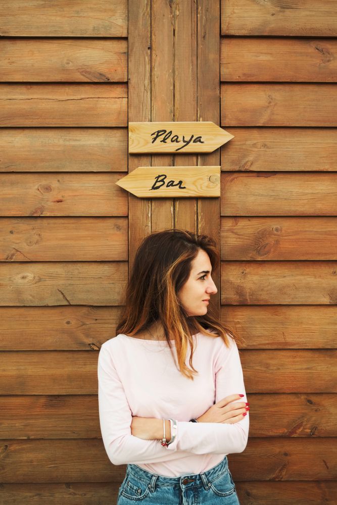 Woman leaning on wooden wall with two signs
