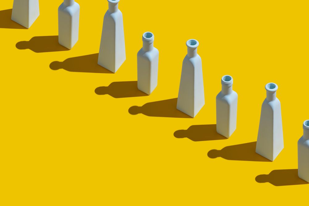 Single row of painted glass bottles on yellow background