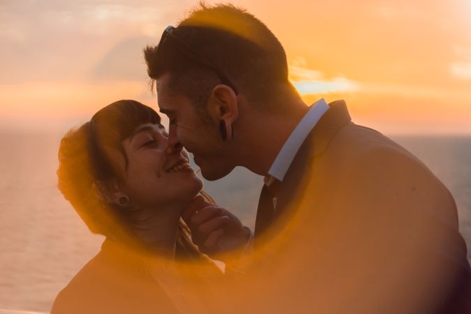 Young people kissing in sunset light on ship
