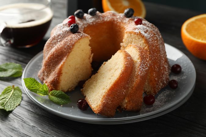 Cake with powdered sugar, berries and mint on wooden background, close up