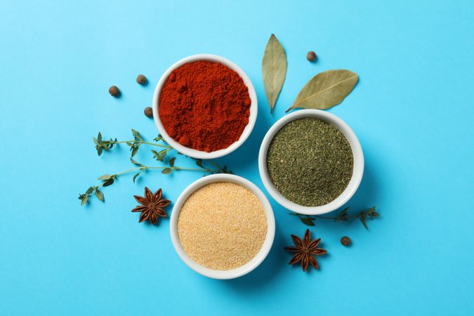 Three bowls of spice on blue table