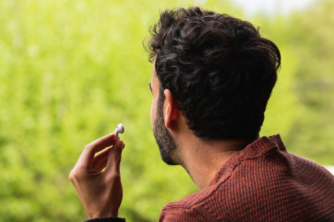 Anonymous man with earbuds against green background
