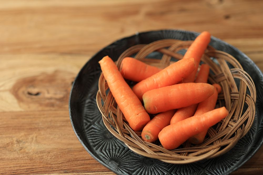 Raw Baby Carrot on Bamboo Plate on Wooden table