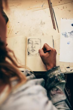 Top view of woman artist sketching on book in her studio