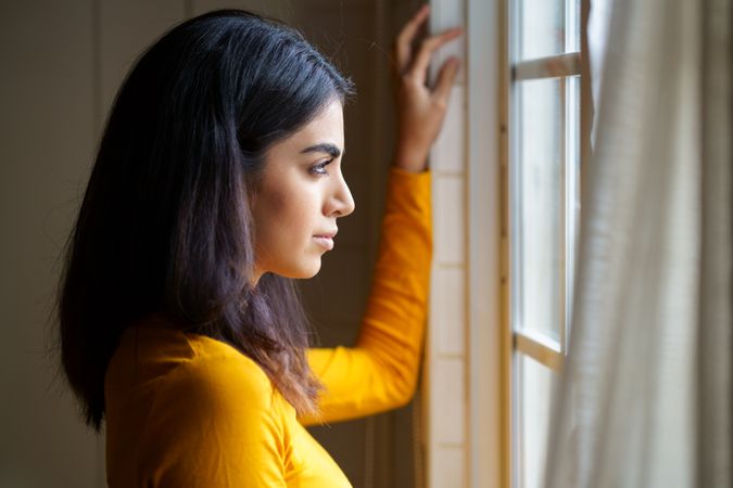 Female opening curtains and looking out the window