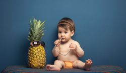 Happy baby playing with a pineapple
