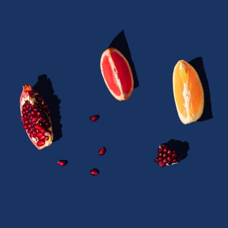 Minimal nature layout with grapefruit, orange and pomegranate slice and navy background
