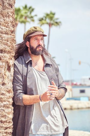 Bearded man standing near palm tree on beach