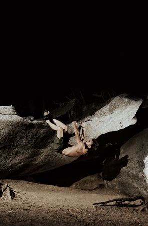 Man practicing rock climbing among large rocks in a forest