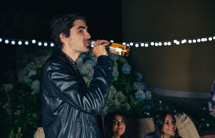 Man drinking bottle of beer at a party on a patio