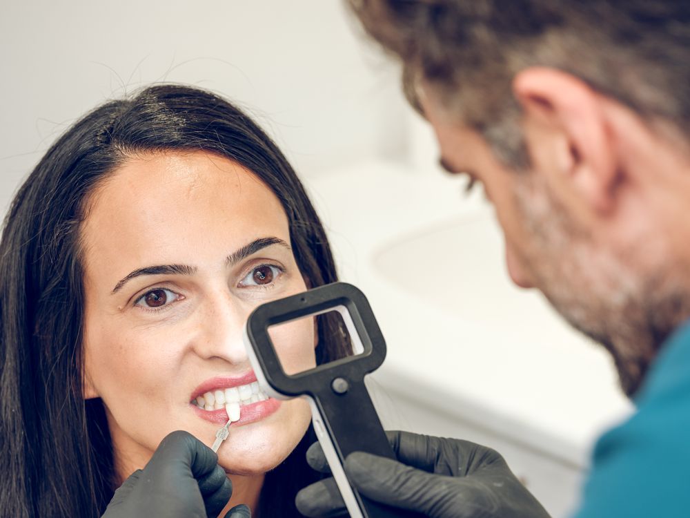 Dentist checking teeth shade of female patient