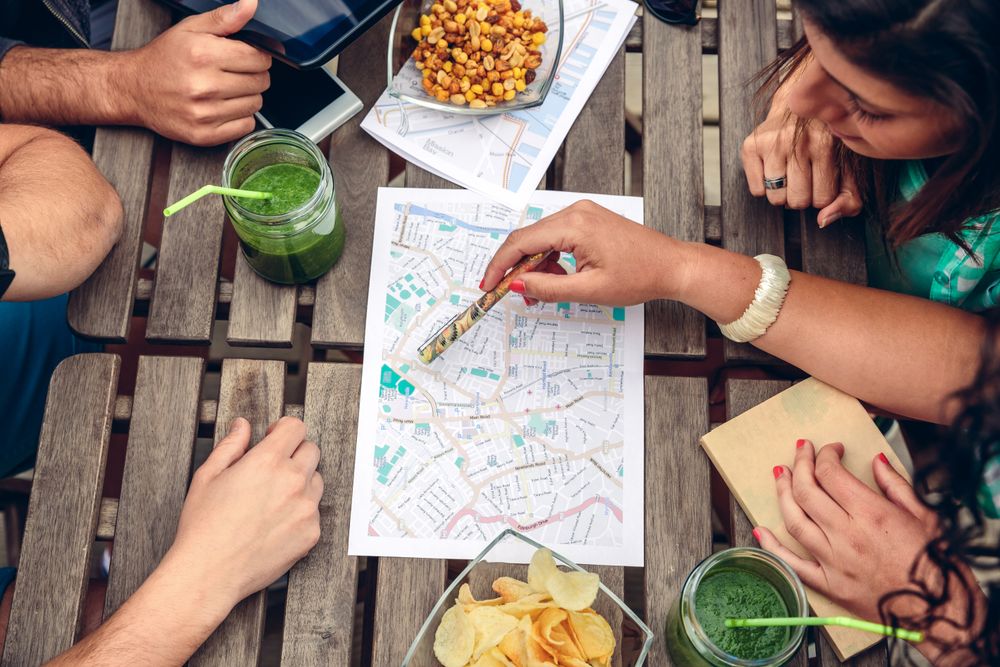 Friends sitting on bench checking maps