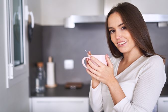 Woman drinking from cup in kitchen