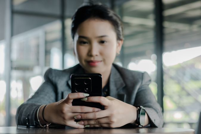 Young professional woman using her smartphone in a modern worksp