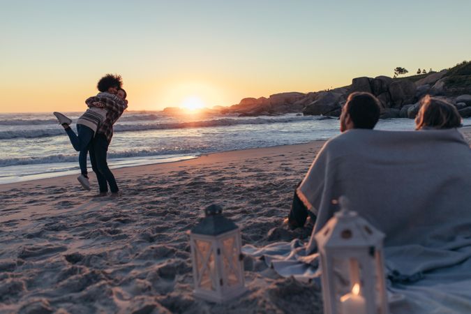 Couple hugging at the beach with people sitting at the front