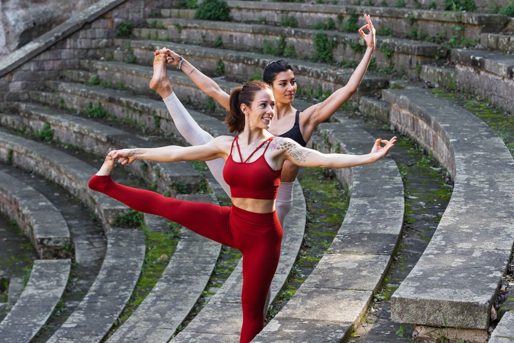 Content women doing yoga in Extended Standing Hand to Toe pose