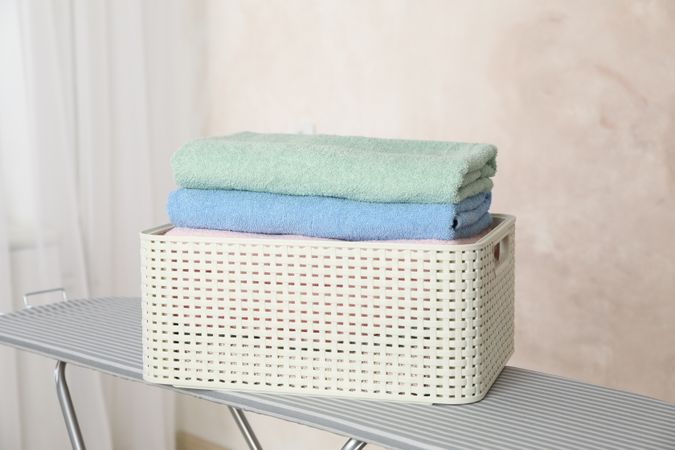 Basket with clean laundry on ironing board, space for text