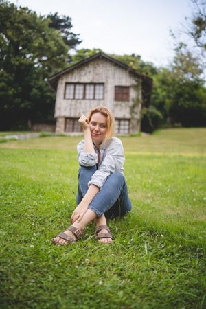 Content female sitting on grass in countryside
