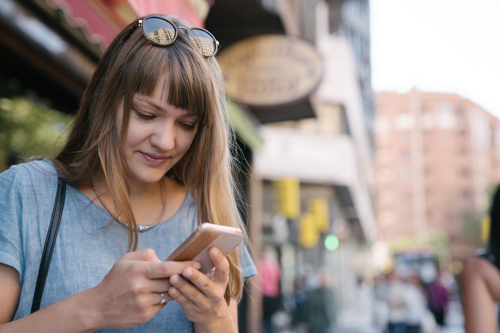 Woman with glasses using smartphone outdoor