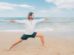 Man training yoga on beach