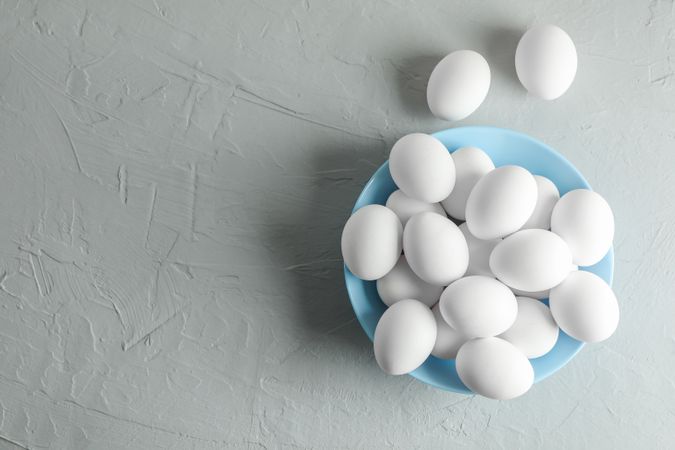 Chicken eggs in plate on gray background, space for text