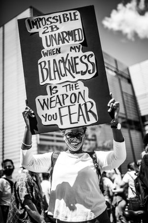 MONTREAL, QUEBEC, CANADA – June 7 2020- Woman in glasses holding a sign at a BLM protest