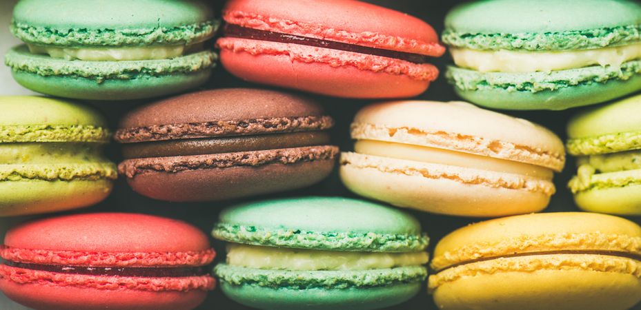 Bright multi-colored macaron pastries tightly stacked, side view, wide composition, close up