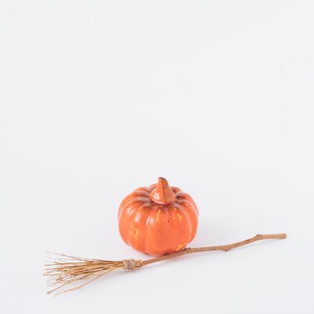 Broomstick and pumpkin on light  background