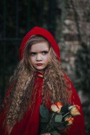 Young girl wearing red cape and holding flowers