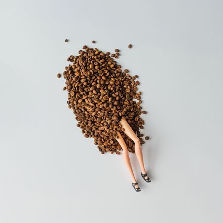 Doll legs emerging from a pile of coffee beans