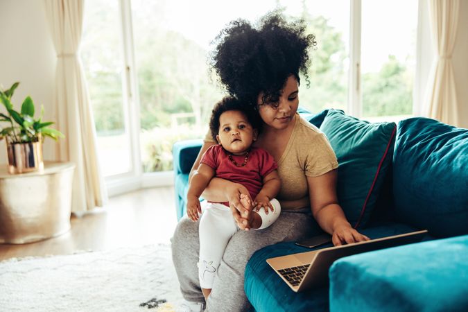 Young mother multitasking at home while caring for her baby