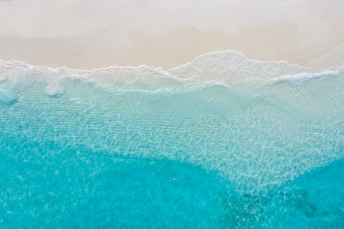 Aerial shot of waves coming in on a tropical beach